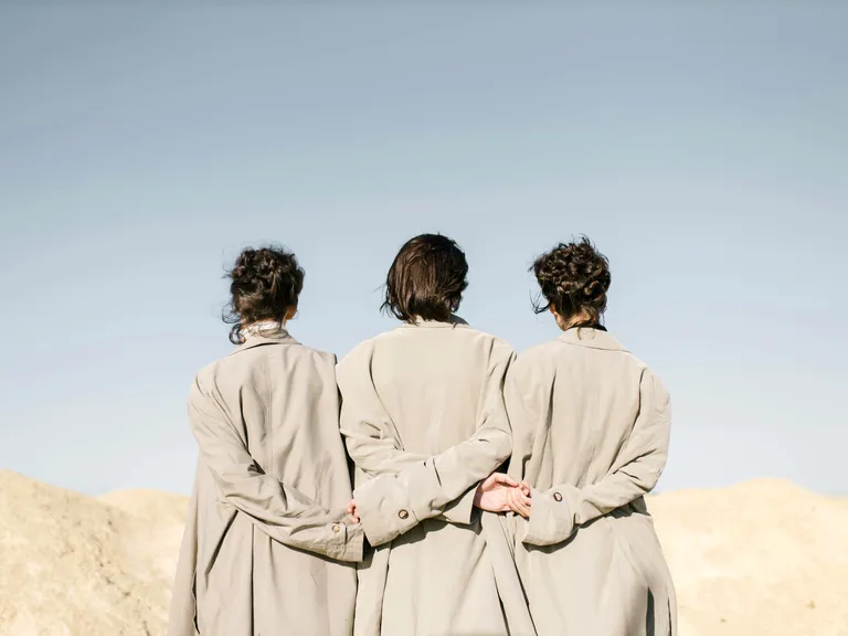 Three women stand back-to-back beneath a bright sky. Symbolic image representing the ellexx Pillar 3a retirement solution.